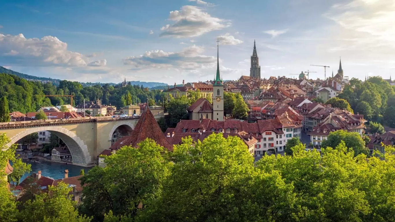Panoramablick über die Altstadt von Bern mit Aare, Nydeggbrücke und Münster bei sonnigem Wetter.