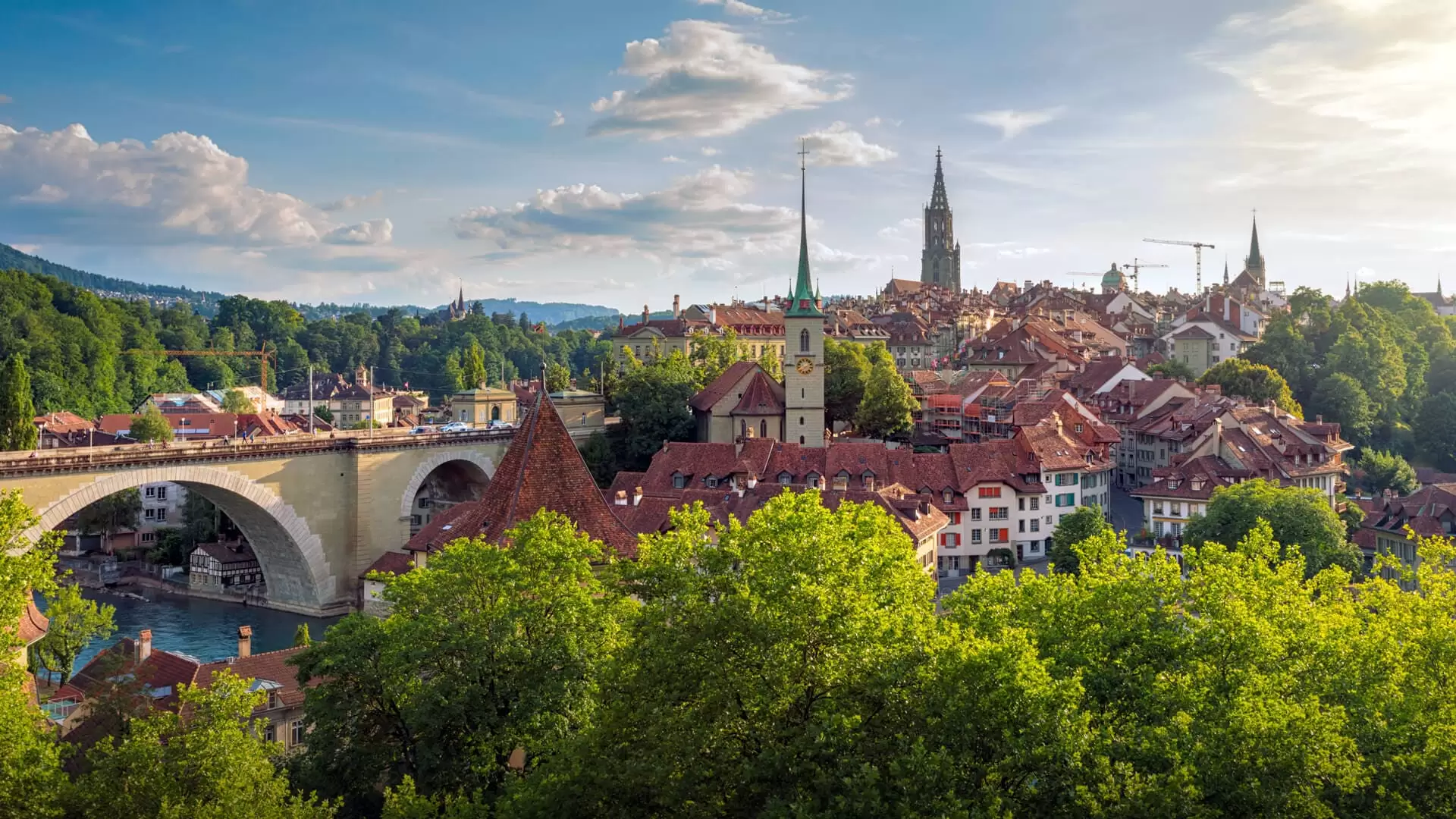 Panoramic view over Bern’s old town with the Aare river, Nydegg Bridge and cathedral in sunny weather.