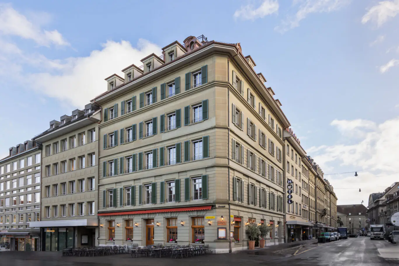 Außenansicht eines Stadthauses mit klassischer Fassade und Hotelbeschriftung an einer belebten Ecke.