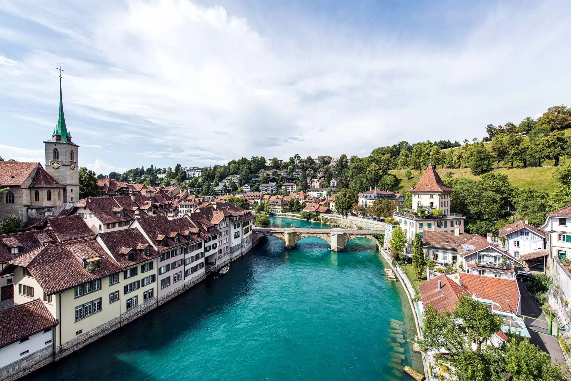 View over Bern’s old town with the Aare river, historic bridge and red rooftops, scenic landscape under a clear sky.