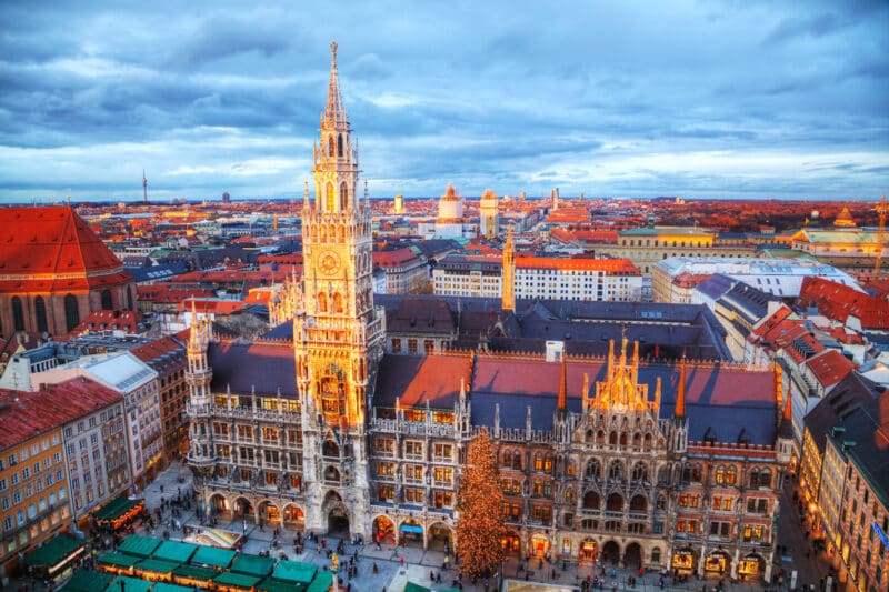 Panoramablick über München mit Marienplatz, Neuem Rathaus und beleuchteter Altstadt bei Sonnenuntergang.