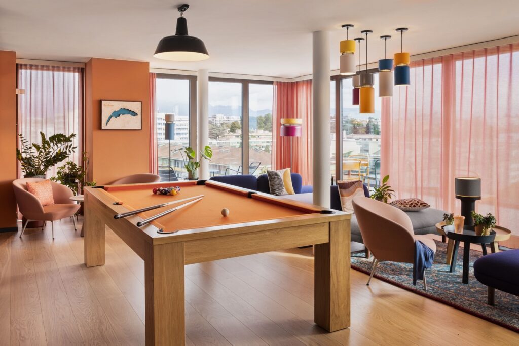 Heller Gemeinschaftsraum mit Billardtisch und Sitzgelegenheiten für entspannte Freizeit im Hotel.