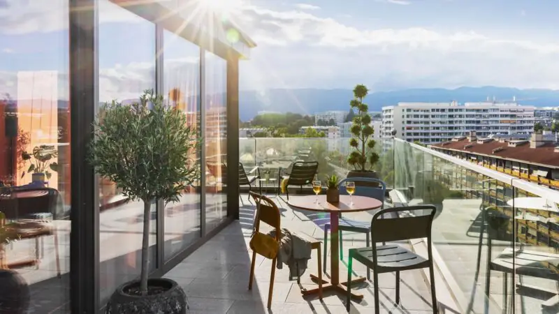 Sonnige Dachterrasse mit moderner Fensterfront, Sitzgruppen und weitem Blick über die Stadt in entspannter Atmosphäre.