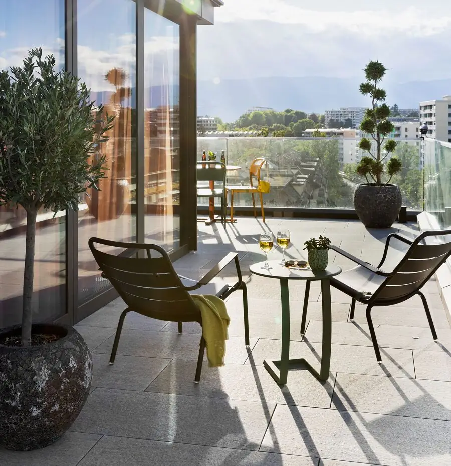 Sunny rooftop terrace with modern glass front, seating areas and wide city views in a relaxed setting.
