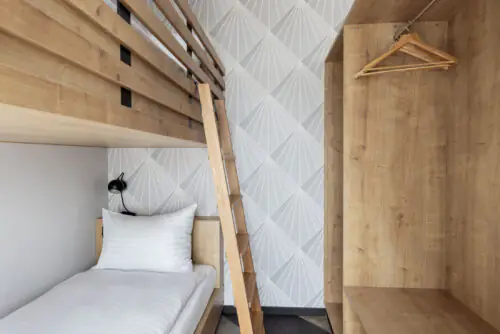 Bunk bed with light wooden frame and open wardrobe as a practical sleeping solution in the studio.