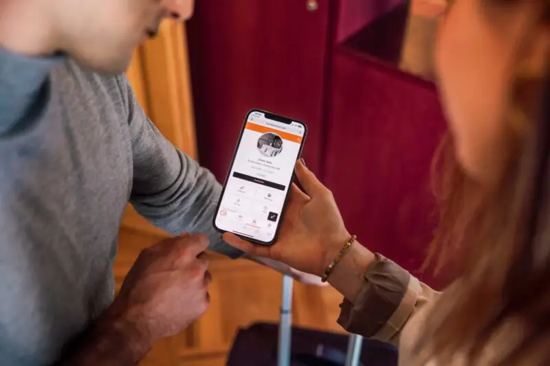Two people using a smartphone for digital booking or information inside a hotel interior space.