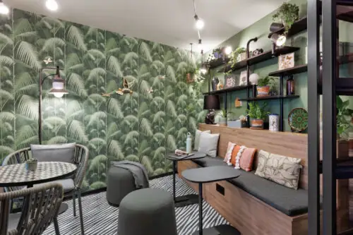 Green loggia with indoor plants, seating, small tables, wall shelf with decorative elements