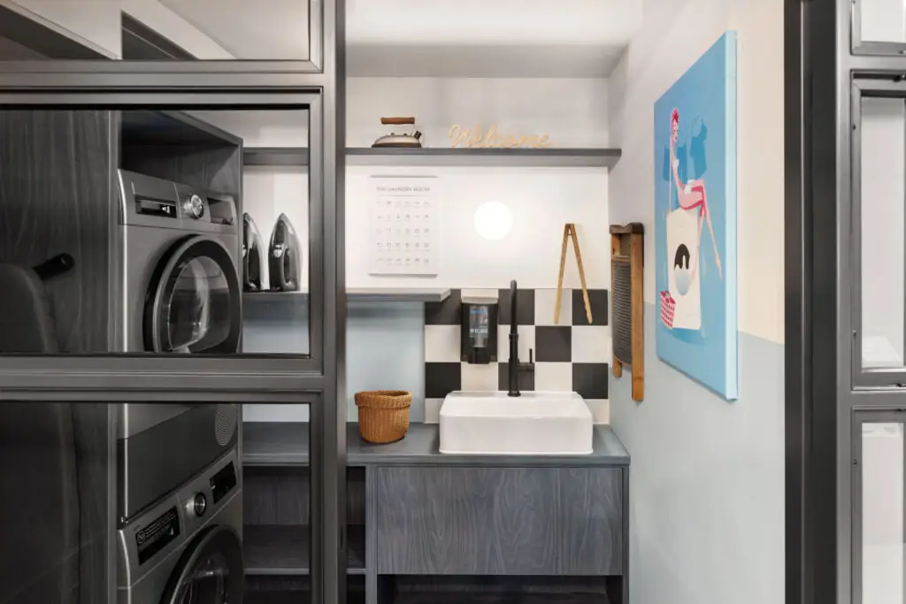 Waschbereich mit Waschmaschine, Trockner, Spüle und schwarzen Einbauschränken im modernen Design.