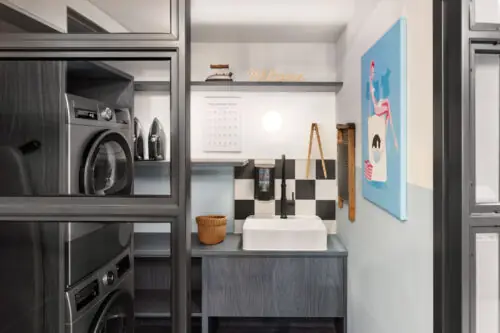 Waschbereich mit Waschmaschine, Trockner, Spüle und schwarzen Einbauschränken im modernen Design.