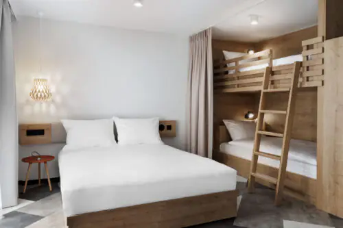 Familienzimmer mit Doppelbett und Etagenbett aus Holz in hellem, minimalistischem Raumdesign.