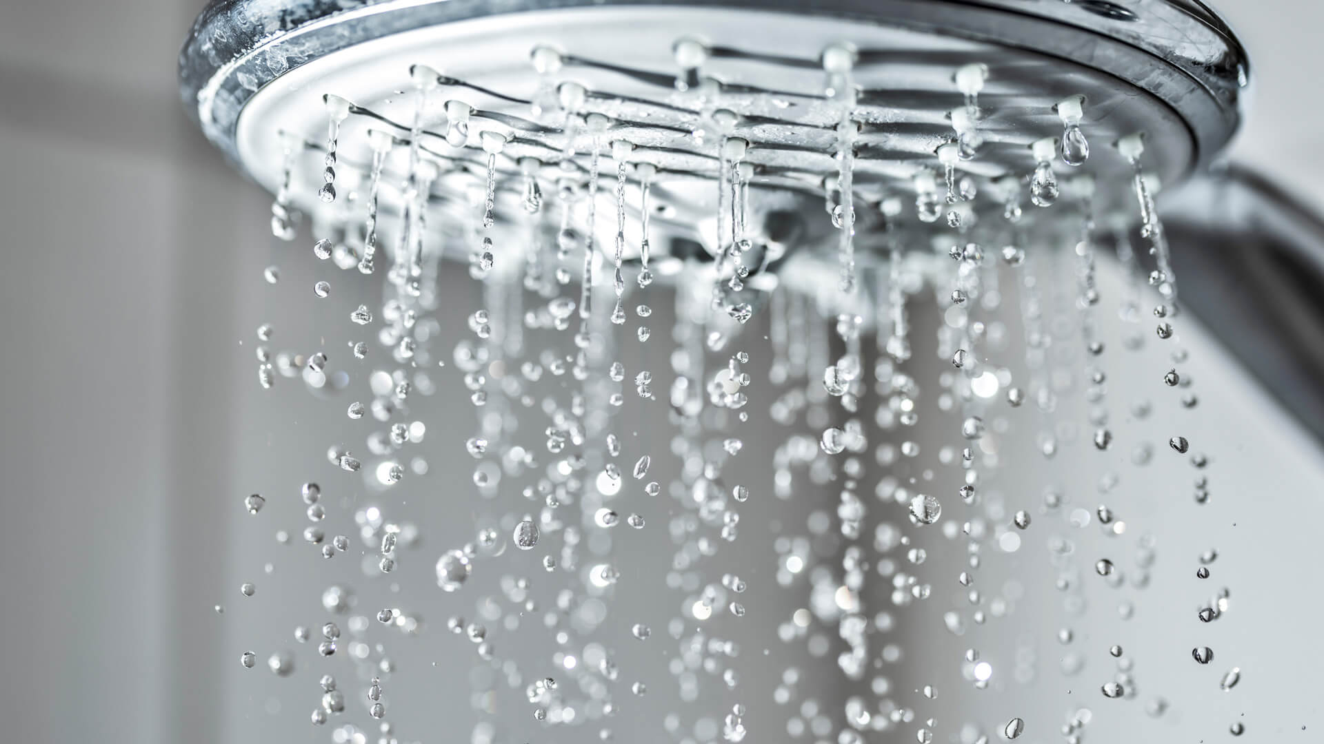A close-up of a shower head with evenly falling water droplets, symbolising a relaxing shower.