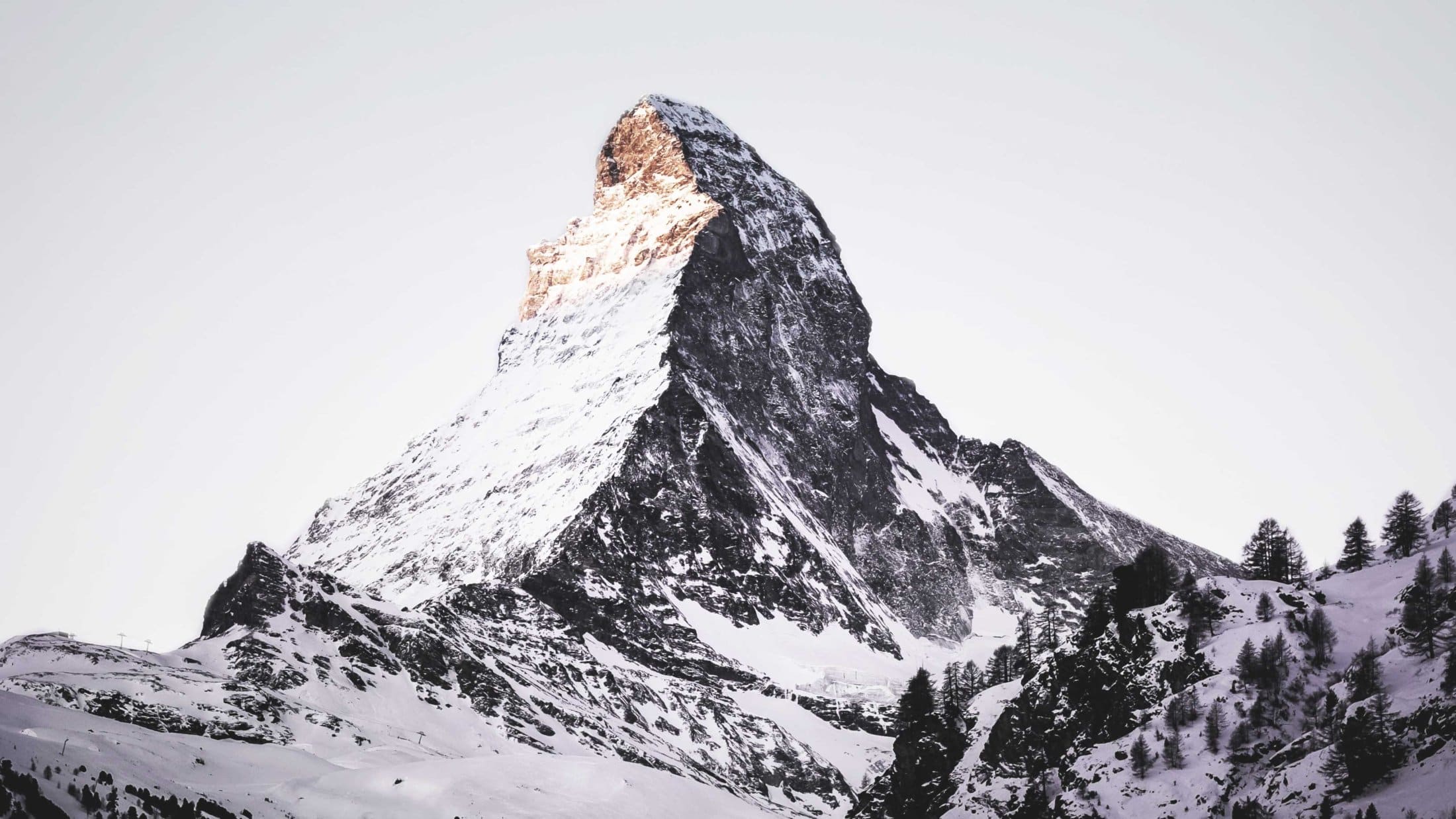 Snow-covered mountain peak in the Alps at sunrise with a dramatic landscape and clear winter atmosphere.