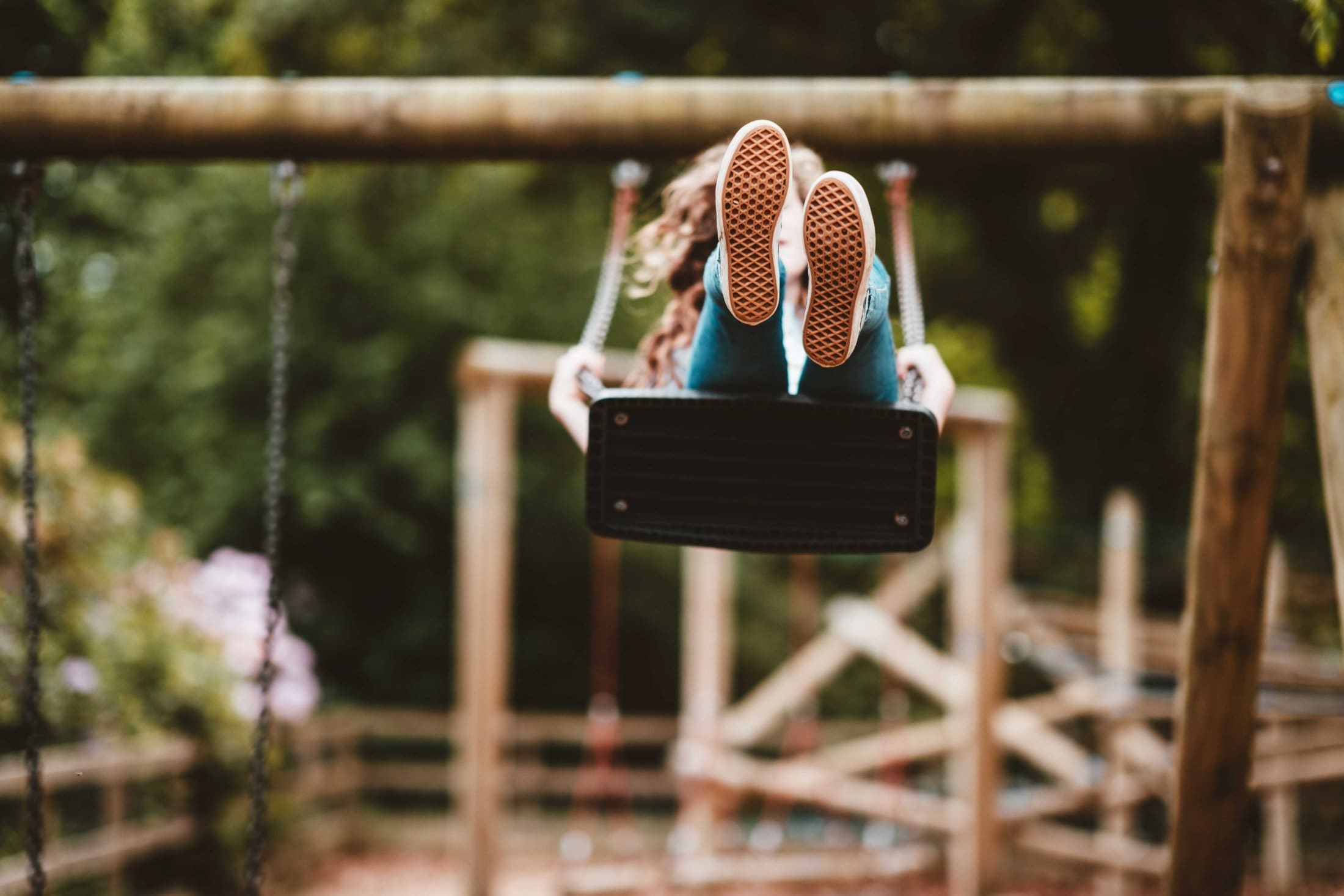 Child happily swings at the playground, enjoying movement and carefree moments in the fresh outdoor air.