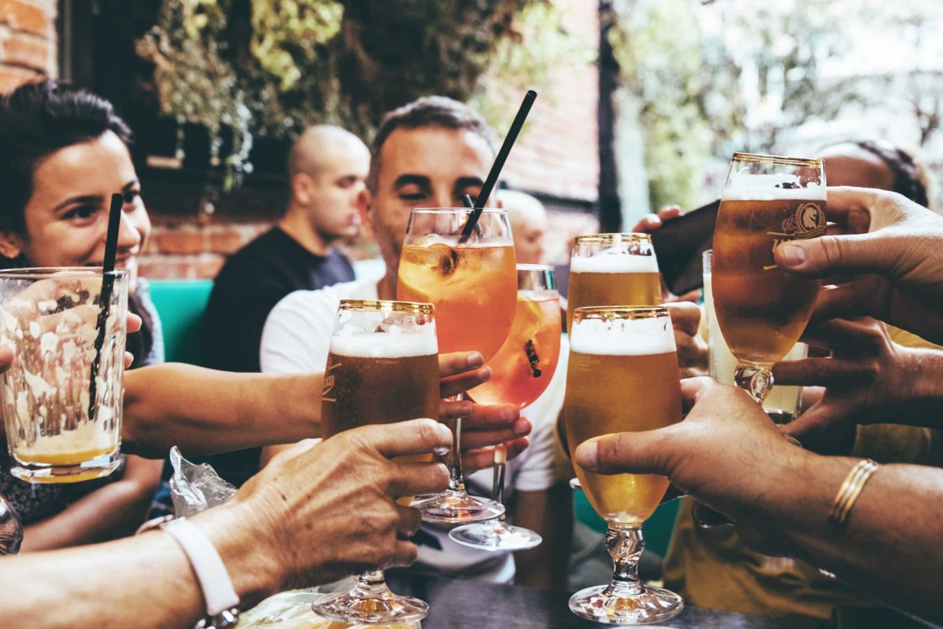 Freunde stoßen draußen mit Bier und Aperol an, genießen gemeinsam entspannte Momente in geselliger Runde.