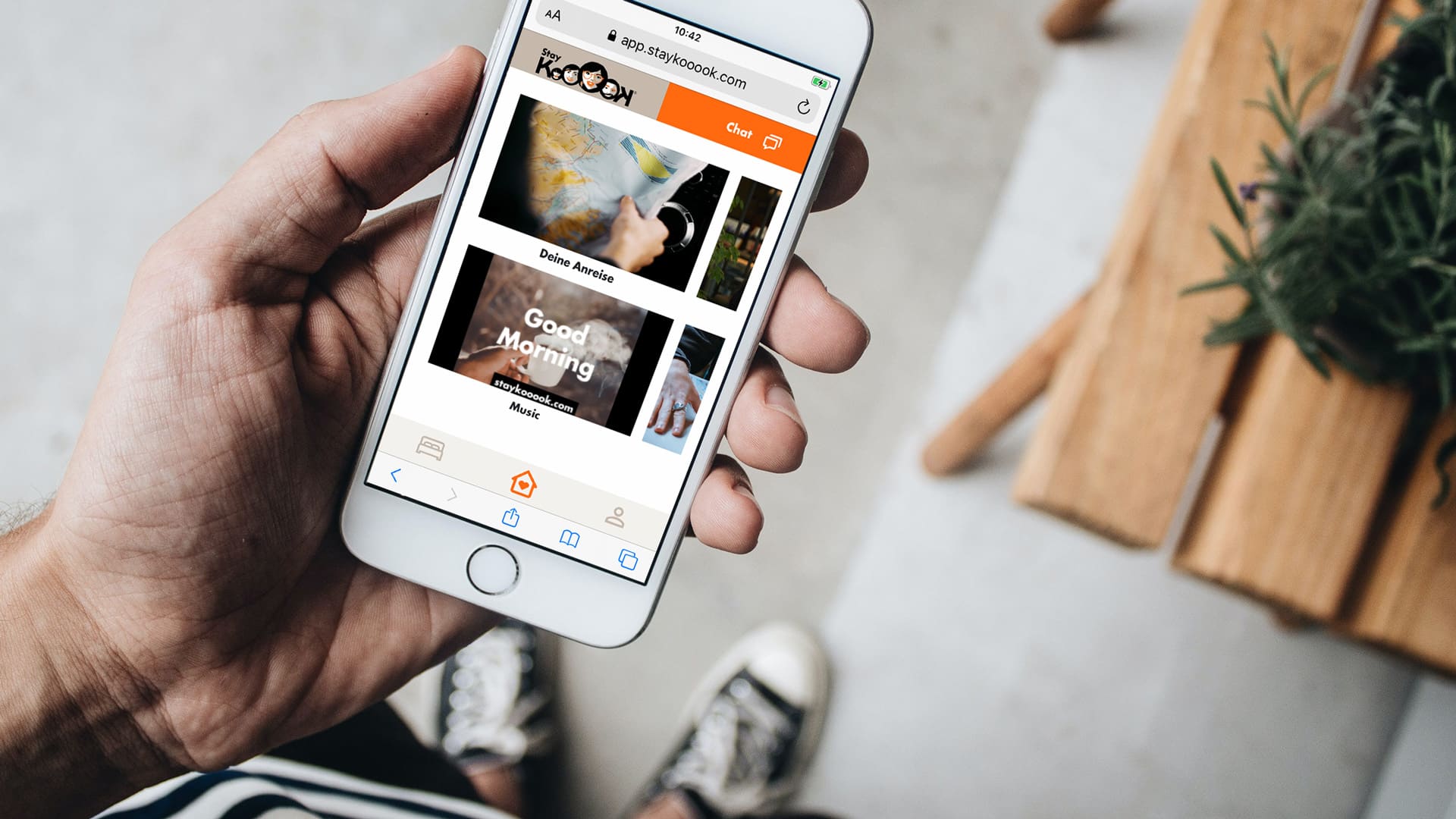 Person hält ein Smartphone mit der Stay KooooK App in der Hand.