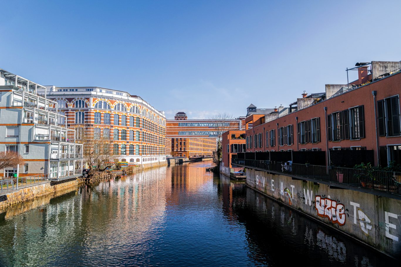 Urbaner Kanal mit historischer Backsteinarchitektur und modernen Wohnhäusern – ein spannender Mix aus Industriecharme und Stadtleben.