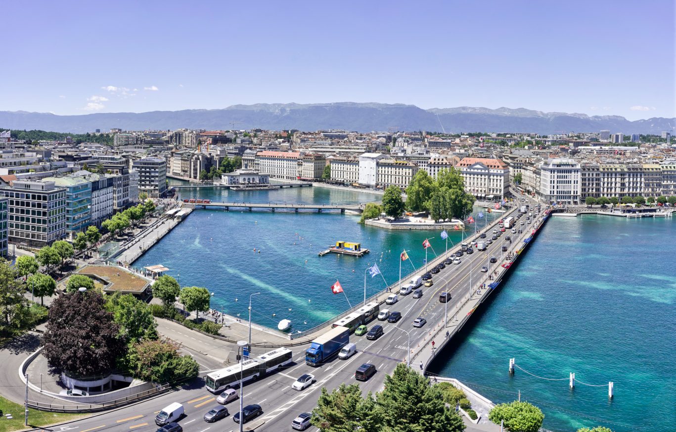 Panorama von Genf mit dem türkisfarbenen Rhône-Ausfluss, der Mont-Blanc-Brücke und Blick auf die Alpen – verbindet urbanes Leben mit beeindruckender Naturkulisse.