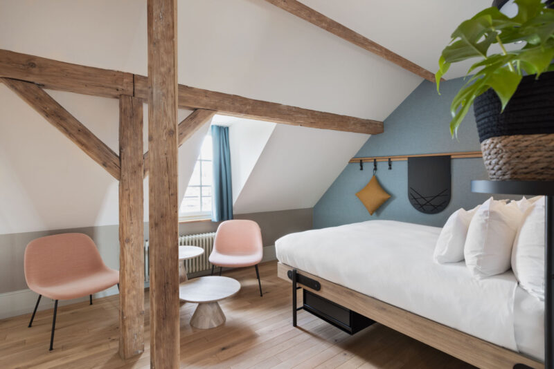 A bright room in Bern city centre with sloping ceilings, exposed wooden beams and a cosy seating area – an urban retreat full of character.