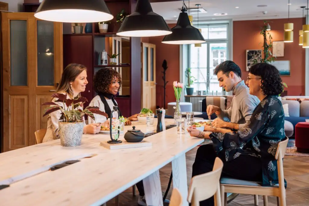 Vier Personen essen gemeinsam am Holztisch, genießen die Atmosphäre und tauschen sich in entspannter Runde aus.