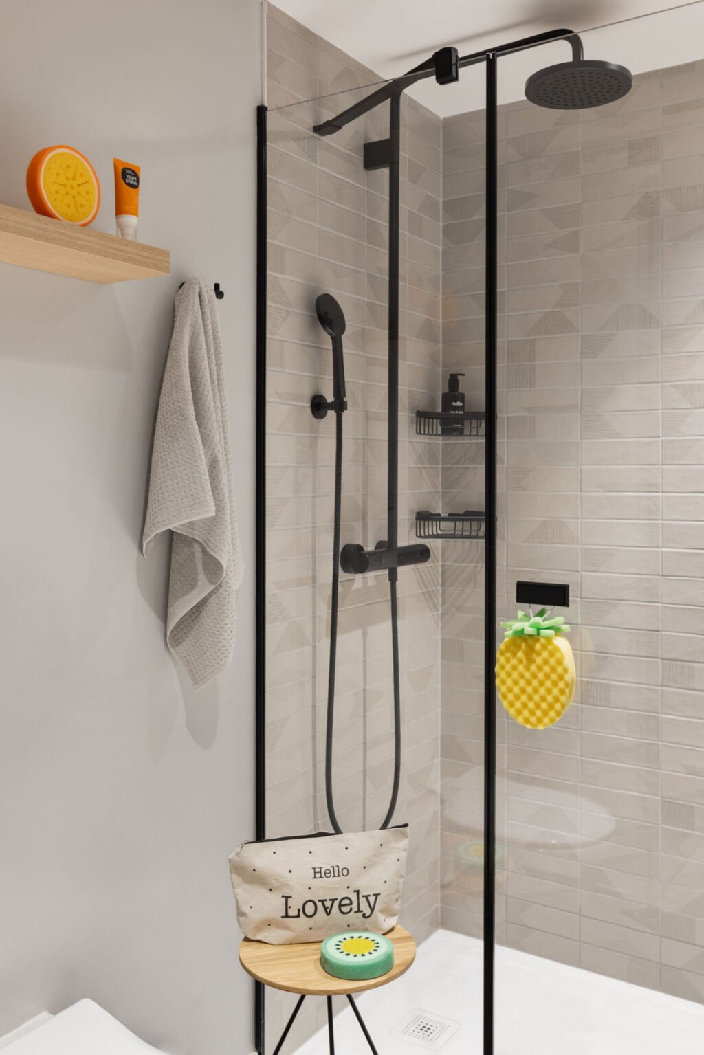 Helles Bad mit Glasdusche, Regen- und Handbrause sowie Badeaccessoires wie Schwamm und weiteren Details.
