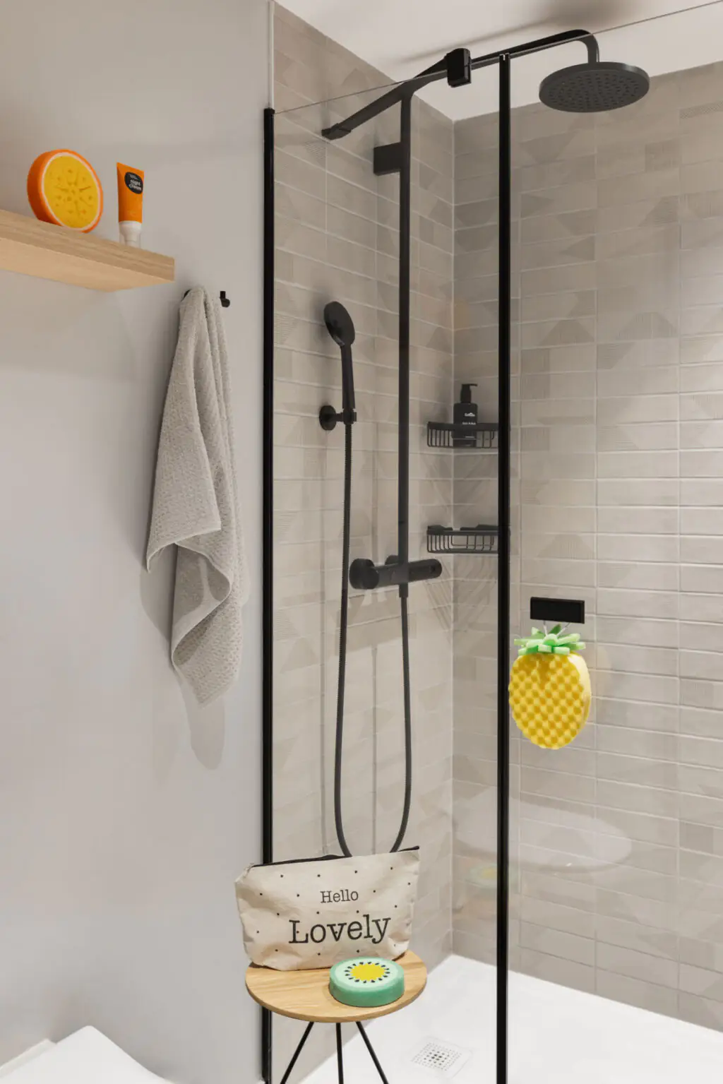 Bright bathroom with glass shower, rain and hand shower plus bath accessories like sponge and details.